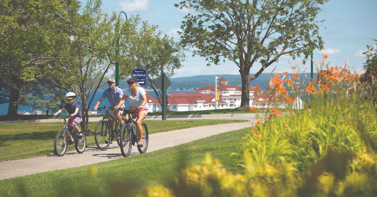 Family riding bicycles along waterfront path with landscaping