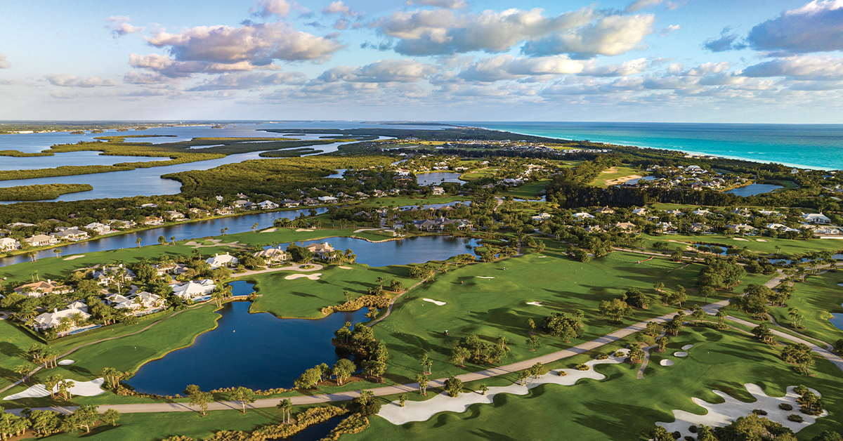 Aerial view of coastal golf course community near the ocean at sunset