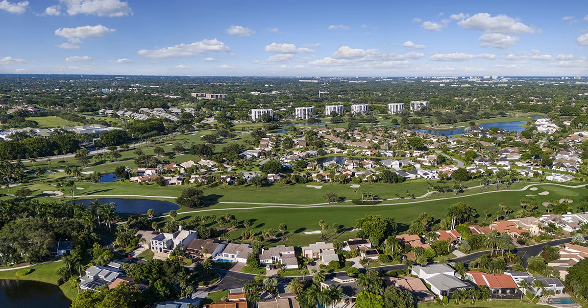 Aerial view of golf course community with homes, lakes, and palm trees