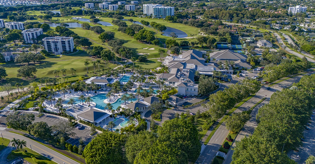 Aerial view of golf club with pool, clubhouse, and surrounding greenery
