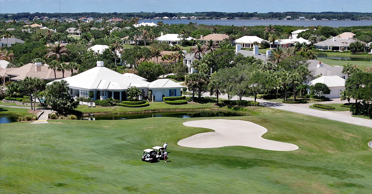 Golf course with sand bunker and homes surrounded by palm trees